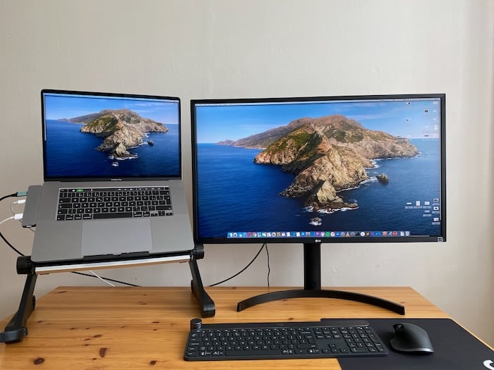 Notebook na stojánku vedle externího monitoru